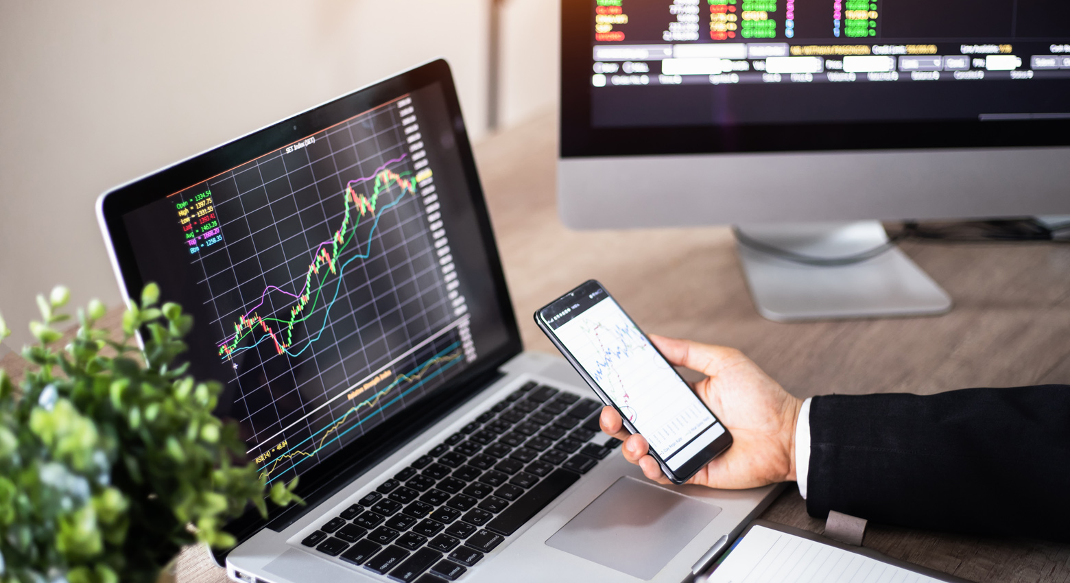 Person holding phone in front of laptop with graphs 