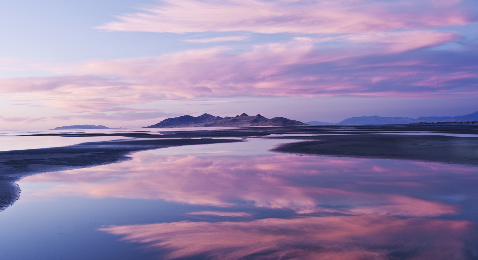 Dawn over calm lake with mountain range in the background