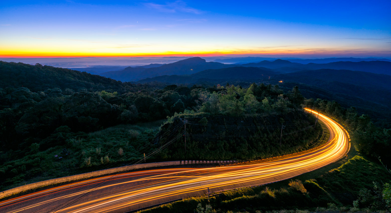 Mountain road at sunset with lights 