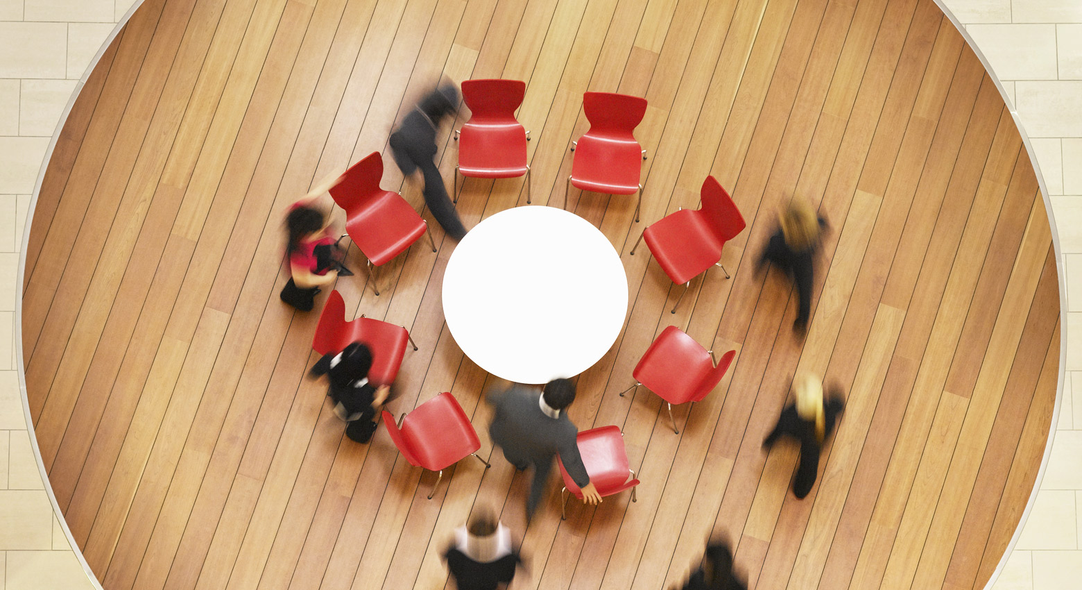 Table with chairs and people standing 