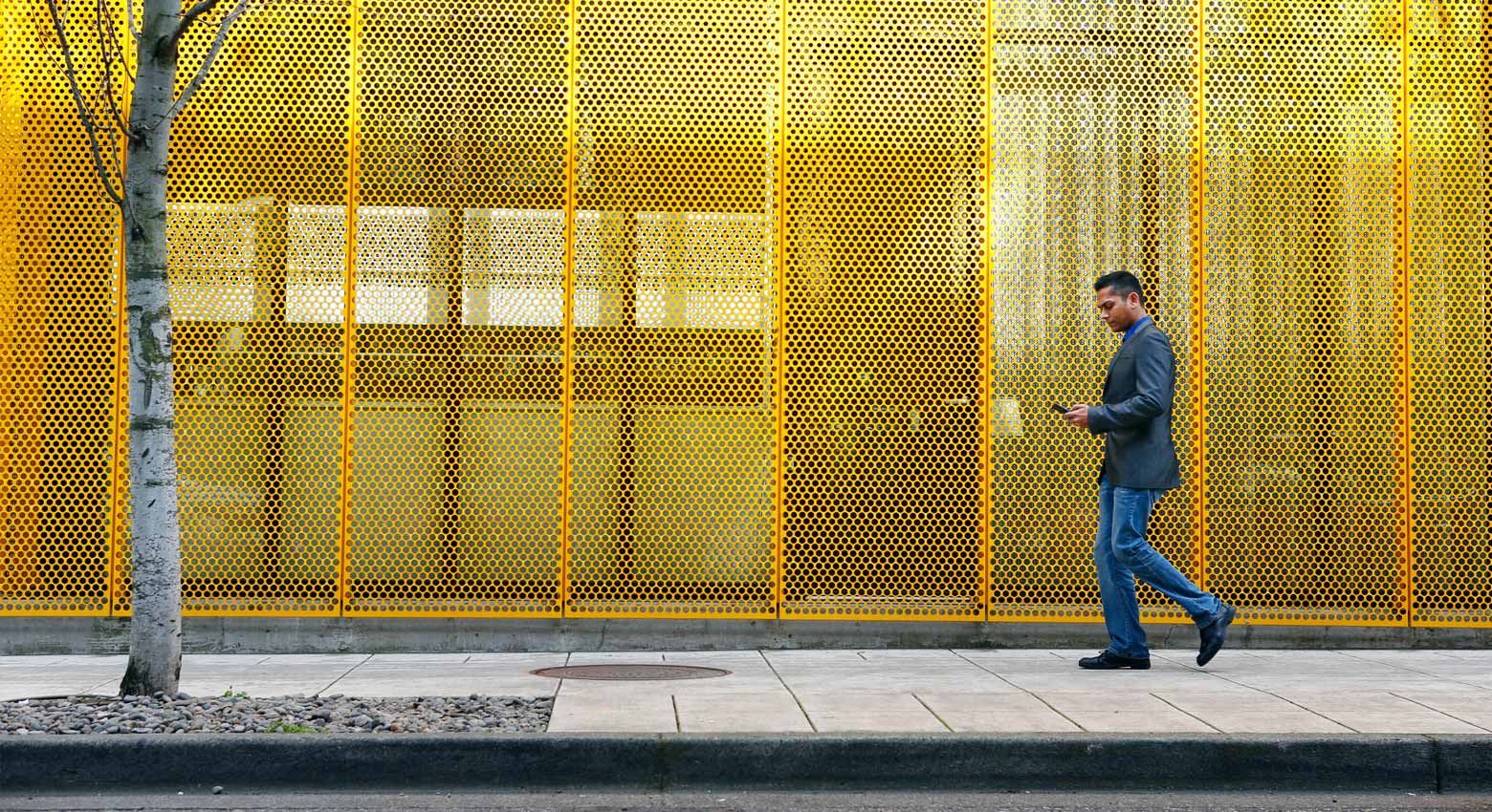 Man walking along yellow wall 